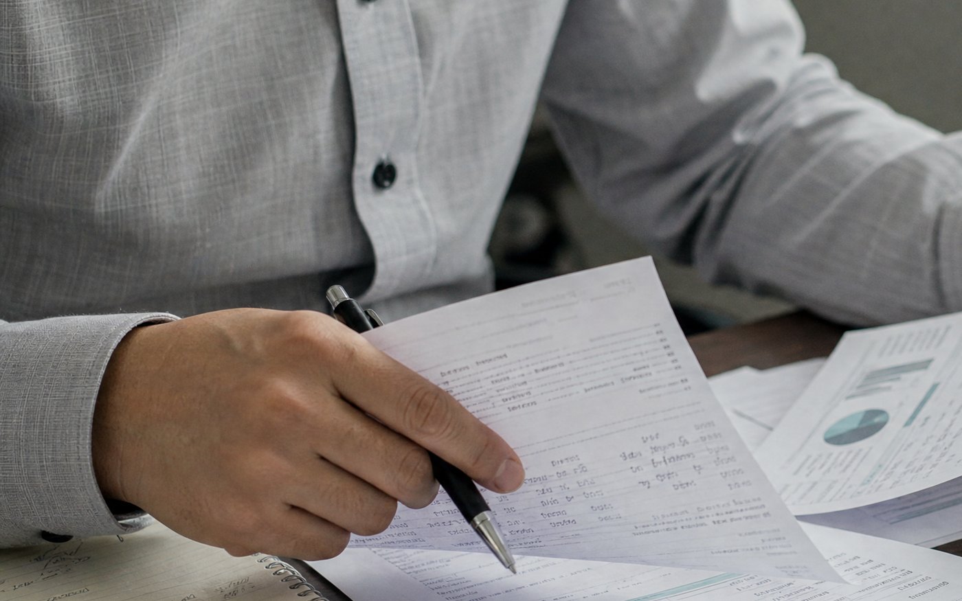 A person going through printed reports with a pen.